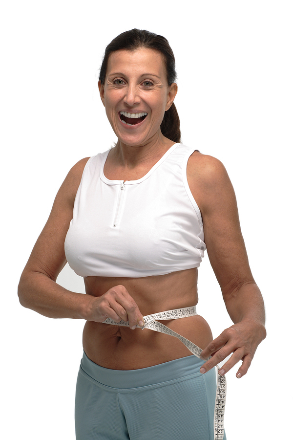 A photo of a happy woman, measuring her waist post-fat freezing treatment.