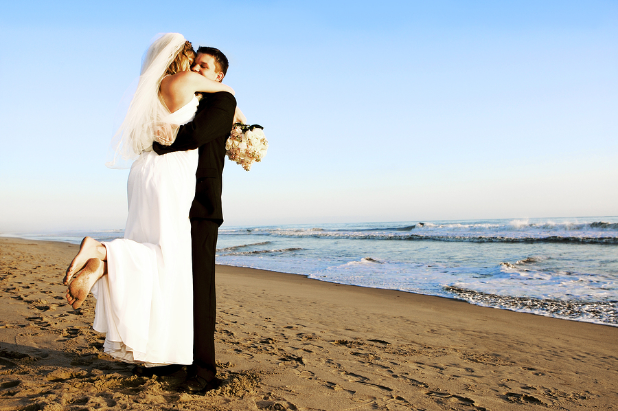 A photo of a couple hugging on a beach on their wedding day.